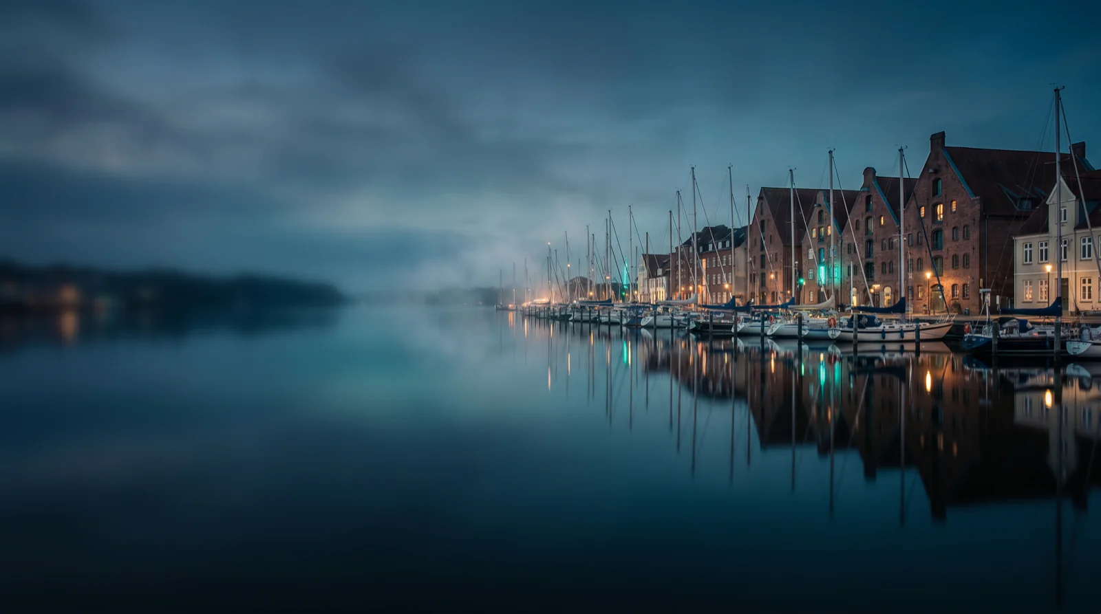 Hafen zur blauen Stunde mit historischen Häusern und Segelbooten am Wasser